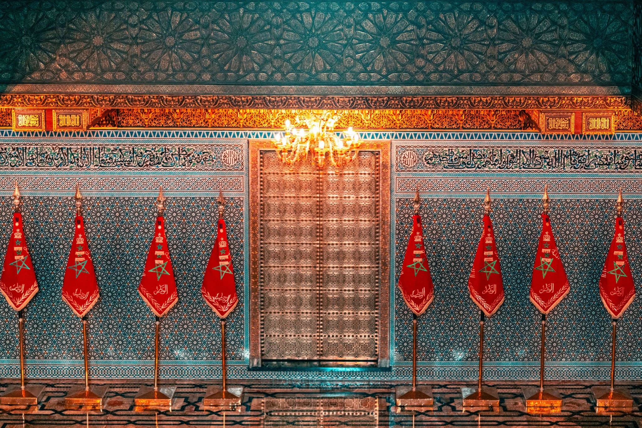 Flags Before the Shrine. Red flags open the scene toward the sanctity of the ornamented facade.