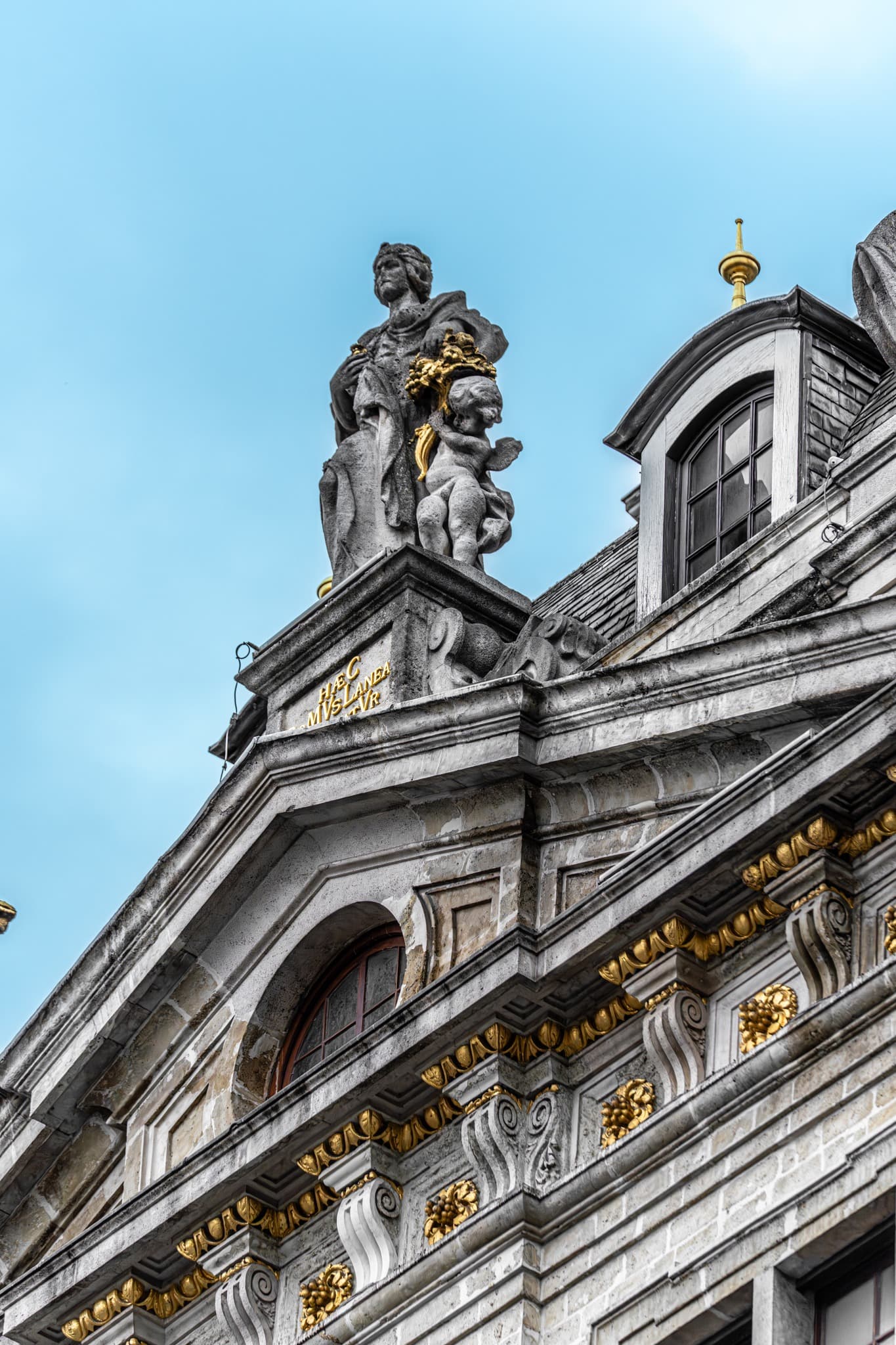 Sentinel on the Pediment. A single figure sets the vertical rhythm of the stone pediment.